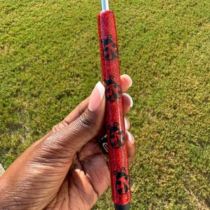 May include: Red glitter pen with black ladybug designs.