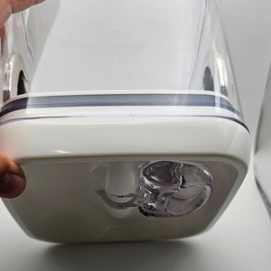 Peut inclure: Un r&eacute;cipient en plastique blanc avec un couvercle transparent et un joint en caoutchouc gris. Le r&eacute;cipient a un bec verseur en plastique transparent avec un bouchon blanc.