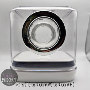 Peut inclure: Un haut-parleur en forme de cube transparent en plastique avec une grille de haut-parleur de couleur chrome. Le haut-parleur mesure 12,7 cm de long, de large et de haut.