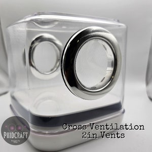 Peut inclure: Un cube en plastique transparent avec deux &eacute;vents de 5 cm. Les &eacute;vents sont ronds et ont un bord en m&eacute;tal argent&eacute;. Le cube a une base blanche avec le texte "Cross Ventilation 2in Vents" imprim&eacute; dessus.