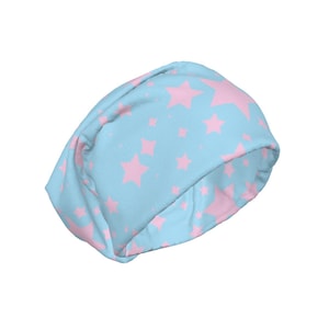 Puede incluir: Un gorro azul claro con un patrón repetido de estrellas rosas. El gorro está hecho de un tejido suave y está diseñado para ser usado en la cabeza. Las estrellas varían en tamaño y están espaciadas uniformemente.