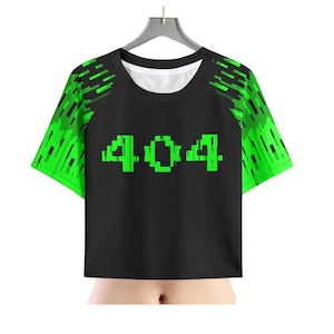 May include: Black crop top with green pixelated "404" text on the front. The sleeves have a green pixelated design. The shirt is hanging on a silver hanger against a white background.