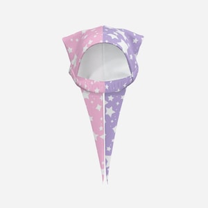 May include: A split-color hood featuring a pastel pink side and a pastel purple side, both covered in a white star pattern. The hood has a rounded opening and two long, pointed fabric tails that hang downward from the front of the garment.