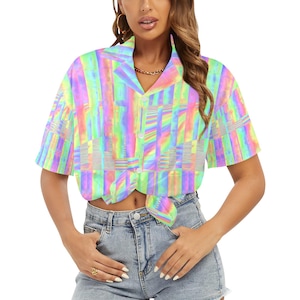 May include: A short-sleeved button-down shirt with a vibrant, abstract pattern in pastel rainbow colors. The shirt is tied at the waist and has a classic collar. The fabric appears lightweight and suitable for warm weather.