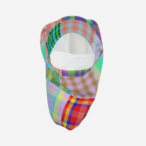Puede incluir: Un pasamontañas con un vibrante patrón de cuadros multicolor con líneas que se cruzan en tonos rojo, amarillo, azul, verde y morado. La tela tiene un diseño de cuadros en tonos pastel en toda la superficie, con una gran abertura circular.
