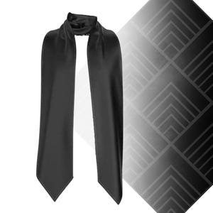 Puede incluir: Una bufanda de satén negro con un diseño drapeado. La bufanda es larga y rectangular, con una textura suave y brillante. La bufanda se muestra sobre un fondo blanco con un patrón geométrico.
