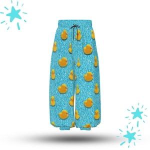 Puede incluir: Pantalones de pijama azules con un estampado de patitos de goma amarillos flotando sobre un fondo acuático. Los pantalones tienen cintura con cordón y un corte holgado. El tema general es juguetón y caprichoso.