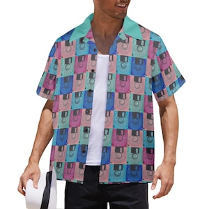 May include: Short-sleeved button-down shirt with a retro floppy disk pattern in shades of pink, blue, and teal. The shirt has a teal collar and is worn over a white undershirt. The shirt is part of a retro-themed clothing collection.