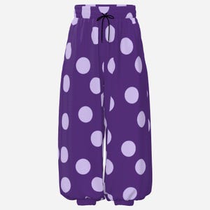 Puede incluir: Pantalones de descanso de color morado oscuro con un patrón repetitivo de lunares grandes de color lavanda claro. Los pantalones tienen una cintura elástica con un cordón negro fino y puños elásticos en la parte inferior de cada pierna.