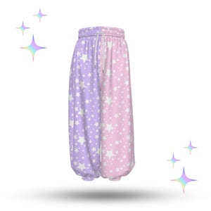 Könnte beinhalten: Eine Jogginghose mit geteiltem Design in Lavendel und Rosa. Jede Seite ist mit einem Muster aus weißen Sternen bedeckt. Die Hose hat einen Kordelzugbund und geraffte Knöchel.
