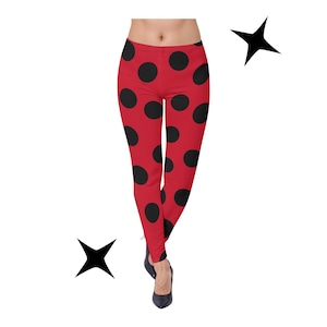 May include: Red leggings with large black polka dots. The leggings are form-fitting and reach the ankles. The model is wearing black heels. The background is white with two black starburst shapes.
