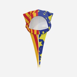 May include: A headscarf featuring a split design with a red and yellow striped pattern on one side and a dark blue background with yellow stars on the other. The fabric has a circular opening and two long, pointed tails hanging down from the front.