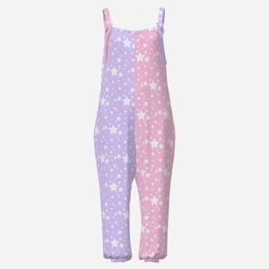 Puede incluir: Un mono sin mangas con un diseño bicolor, con el lado izquierdo de color violeta claro y el lado derecho de color rosa claro. Toda la prenda está cubierta con un patrón de estrellas blancas de varios tamaños y tiene tirantes finos con lazos.