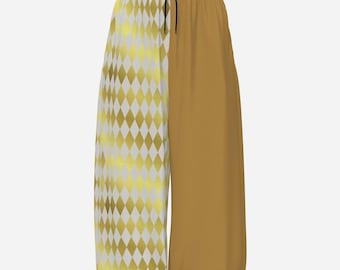 May include: Sweatpants featuring a split design with a white and gold diamond harlequin pattern on the left leg and a solid mustard yellow color on the right leg. The garment includes an elastic waistband with a black drawstring cord at the center.