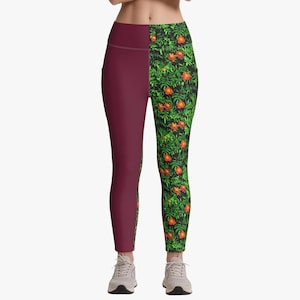May include: High-waisted leggings featuring a split-leg design. The left leg is a solid deep maroon color, while the right leg displays a vibrant botanical pattern with orange flowers and green foliage set against a black background.