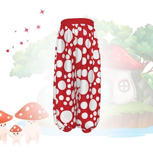 May include: Red and white polka dot pants with a red waistband. The pants have a loose, comfortable fit. The background features a whimsical illustration of mushrooms and a fairy house.