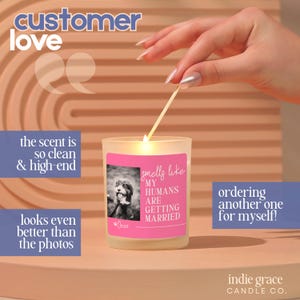 Op de afbeelding: Een brandende kaars in een glazen pot met een roze label met de tekst "smells like my humans are getting married". Het label bevat een zwart-wit foto van een hond. De tekst "customer love" staat bovenaan.