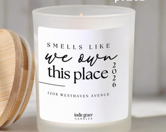 May include: A frosted glass candle with a wooden lid. The candle has a white label with the text "Smells Like We Own This Place 2026" and "1208 Westhaven Avenue". The words "hand poured" are also visible.