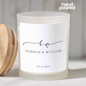 May include: A frosted glass candle jar with a bamboo lid, featuring a white label with the text hand poured, the initials h+w, the names HANNAH & WILLIAM, and the date 06.14.2026 in black serif and script fonts on the front of the container.