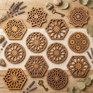 Op de afbeelding: Een verzameling ingewikkeld gesneden houten onderzetters in verschillende geometrische vormen, waaronder zeshoeken, cirkels en sterren. De onderzetters hebben een warme bruine kleur en hebben gedetailleerde opengewerkte patronen. Decoratieve sleutels en takjes lavendel en eucalyptus zijn rond de onderzetters gerangschikt.