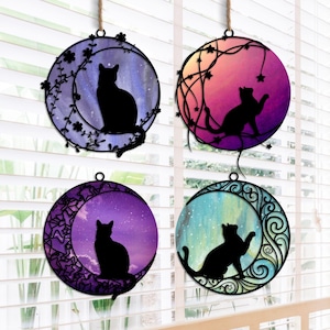 May include: Four round, metal wall hangings with a crescent moon design. Each hanging features a black silhouette of a cat in a different pose against a watercolor background. The backgrounds are purple, pink, blue, and green.