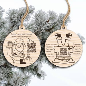 Könnte beinhalten: Zwei Weihnachtsbaumschmuck aus hellem Holz. Einer zeigt den Weihnachtsmann auf der Toilette mit dem Text: „Der Weihnachtsmann liefert gerade seine eigene Speziallieferung ab“. Der andere zeigt die Beine des Weihnachtsmanns in einem Schornstein mit dem Text: „Die Express-Lieferoption hat ihre Schluckauf“.