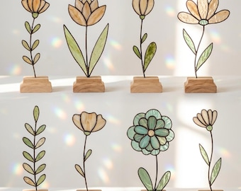 May include: A collection of eight stained glass flower sculptures. Each flower is a different design, with varying colors of amber, green, and blue. The flowers are mounted on small, rectangular wooden bases, creating a decorative display.