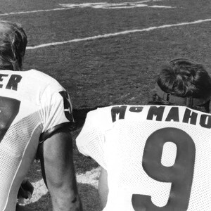 May include: Two football players in uniform, one with the name "THAYER" and the number "17" on their jersey, the other with the name "MC MAHON" and the number "9" on their jersey.