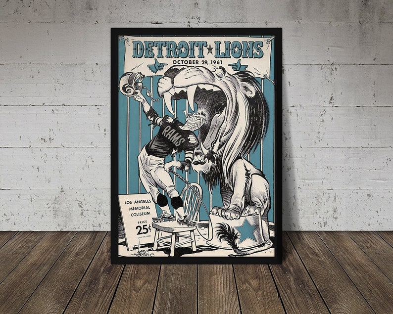 May include: Vintage Detroit Lions poster from October 29, 1961, featuring a stylized illustration of a football player and a lion. The poster has a black frame and is displayed on a wooden surface. The poster includes the text "Detroit Lions" and "Los Angeles Memorial Coliseum".