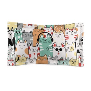 May include: A rectangular pillowcase featuring a repeating pattern of cartoon cats in various colors and designs. The cats have different expressions and accessories, including headphones and sunglasses. The background is white.