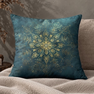 May include: A square throw pillow featuring a deep teal background with a prominent, intricate gold mandala pattern centred on the front. The design displays symmetrical floral and geometric motifs radiating from the centre in metallic gold.