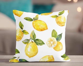 May include: White square throw pillow with a watercolor pattern of yellow lemons and green leaves. The lemons are whole and sliced, creating a fresh, summery design. The pillow is a decorative accent for a sofa or bed.