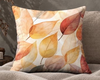 May include: A square throw pillow featuring a watercolor-style pattern of overlapping autumn leaves in shades of orange, yellow, red, and brown against a white background. The leaves have visible veins and translucent, layered textures.