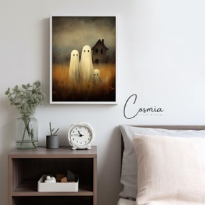 May include: A framed art print featuring three white ghost figures in a field of tall, golden grass, with a spooky house in the background. The artwork has a vintage, slightly blurred aesthetic, perfect for Halloween decor.