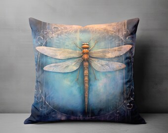 May include: Square cushion with a detailed illustration of a dragonfly. The dragonfly is in shades of orange and beige, set against a blue and teal background. The cushion has a dark blue border.