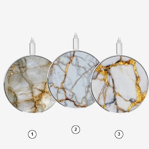 Puede incluir: Tres cargadores inalámbricos circulares con un patrón similar al mármol. El cargador 1 presenta un diseño beige con vetas doradas. El cargador 2 tiene un patrón blanco con vetas doradas. El cargador 3 muestra un diseño blanco con vetas doradas.