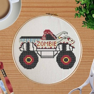 Puede incluir: Un camión monstruo blanco con neumáticos rojos y negros y una caja de carga a rayas rojas y blancas. El camión está etiquetado como "ZOMBIE" y tiene un brazo y una mano de zombi que salen de la caja de carga.