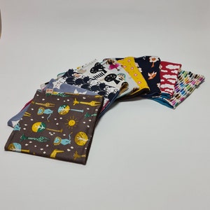Könnte beinhalten: Ein Set aus zehn Stoffquadraten mit verschiedenen bunten Mustern, darunter Tiere, geometrische Formen und abstrakte Designs. Die Quadrate sind aus weichem Baumwollstoff gefertigt und eignen sich perfekt für Bastelprojekte.