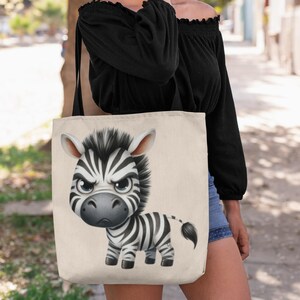 Può includere: Una borsa tote beige con una zebra di cartone animato in bianco e nero con un'espressione arrabbiata. La zebra ha strisce nere e uno sfondo bianco.