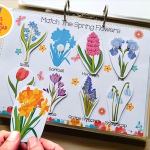 May include: A colorful educational activity featuring spring flowers. The image shows a binder with flower cutouts labeled with names like Scilla, Daffodil, and Hyacinth. The text "Match The Spring Flowers" is visible. The image also includes two markers and the text "57 PAGES DIGITAL DOWNLOAD PDF".