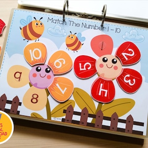 May include: A colorful educational game with the text "Match The Number 1-10". The game features flower-shaped cards with numbers and matching number pieces. Includes bee illustrations and dry-erase markers. A digital download is available.