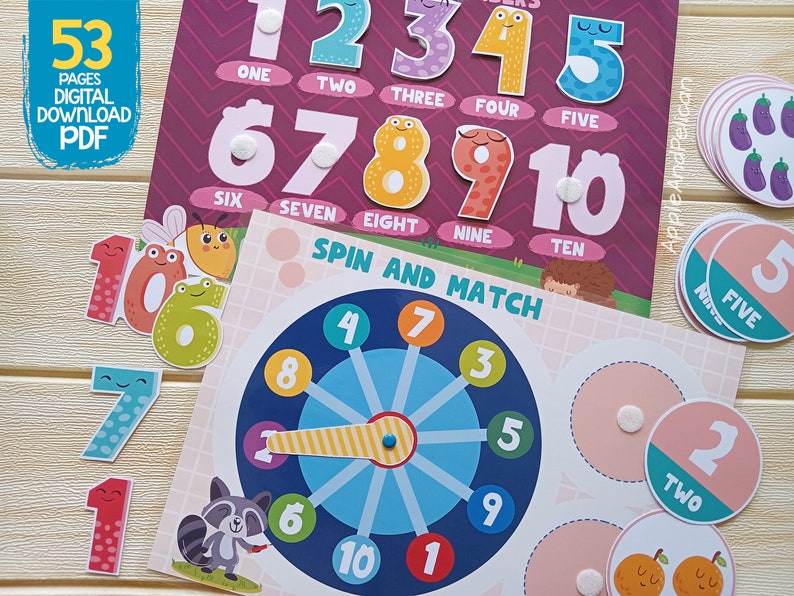 May include: A colorful set of educational learning materials for kids featuring numbers 1 through 10. The set includes a spin and match game with a colorful wheel and number cards. The numbers are illustrated with cute cartoon characters.