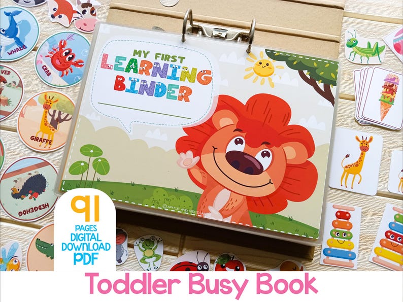 May include: A colorful binder with the text "My First Learning Binder" on the cover. The binder is open to a page with a cartoon lion illustration. The binder is surrounded by various colorful flashcards with animal and object illustrations. The text "91 Pages Digital Download PDF" is on a pink and blue label.