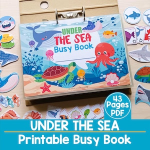 Op de afbeelding: Een kleurrijk "Under the Sea Busy Book" met illustraties van zeedieren zoals walvissen, octopussen en schildpadden. De omslag toont de titel en de tekst "43 Pages PDF". Extra zeethema uitsparingen en kaarten zijn zichtbaar.