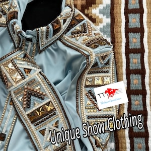 Könnte beinhalten: Hellblaue Showjacke mit aufwendigen Verzierungen. Die Jacke weist komplizierte Muster aus braunen, goldenen und klaren Strasssteinen und Nieten auf. Der Text "Unique Show Clothing" ist auf der Jacke zu sehen.