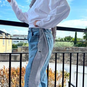 Peut inclure: Un haut à manches longues blanc associé à un jean bleu en denim doté d'un large empiècement latéral en jersey gris. Le jean présente un petit logo crocodile vert sur le côté, une fermeture à bouton et une coupe classique à cinq poches.