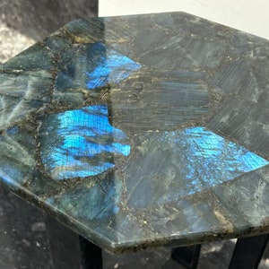 May include: Octagonal table top made of iridescent blue and green labradorite stone. The table top is polished and has a smooth finish.