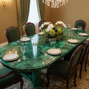 Può includere: Un tavolo da pranzo ovale con superficie verde malachite, apparecchiato per una cena formale. Il tavolo è circondato da sedie imbottite verdi con struttura in legno scuro. Un centrotavola floreale e un lampadario di cristallo aggiungono eleganza.