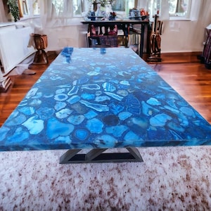 May include: A large, rectangular dining table with a blue agate top. The table has a modern, geometric metal base.