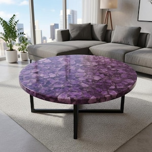 May include: A round coffee table with a vibrant purple amethyst top. The tabletop is made of polished amethyst pieces, and the base is a black metal frame. The table is set on a light gray rug in a modern living room.